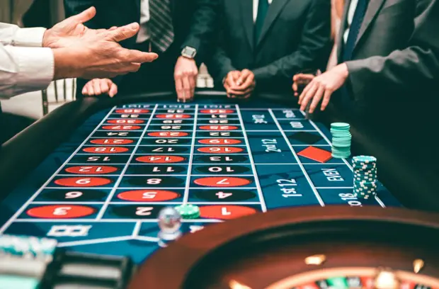 Joueurs autour d’une table de roulette dans un casino français en ligne, misant sur les numéros pour maximiser leurs chances de gain